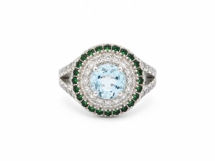 Bague en or blanc 18 carats ornée d'une aigue-marine ovale, d'un entourage de diamants et de tsavorites vertes, bijou raffiné de haute joaillerie.